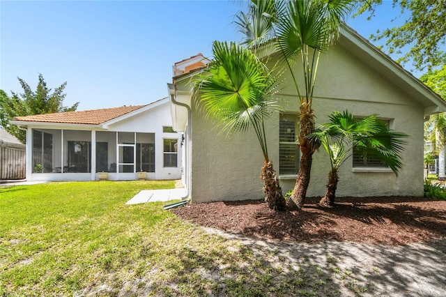 441 Village Dr, Tarpon Springs, FL 34689 - back of house featuring a sunroom, stucco siding, and a lawn