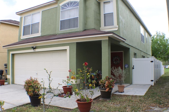 view of front of house featuring a gate, a garage, fence, and stucco siding