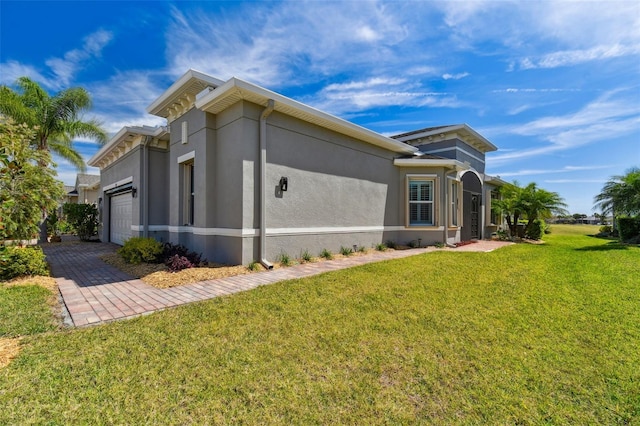 view of property exterior with an attached garage, a lawn, driveway, and stucco siding
