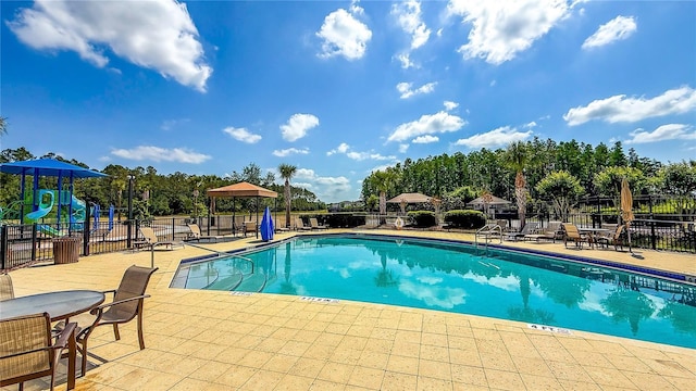 community pool featuring a patio area, fence, and playground community