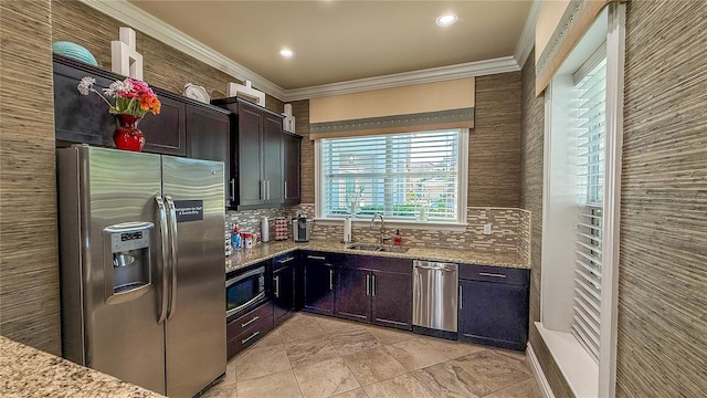 kitchen featuring stainless steel appliances, ornamental molding, a sink, light stone countertops, and decorative backsplash