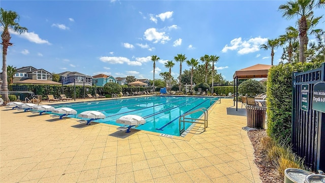 community pool featuring a residential view, a patio area, and fence