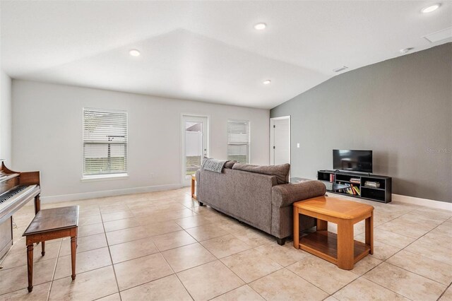 living room featuring light tile patterned floors, baseboards, and vaulted ceiling