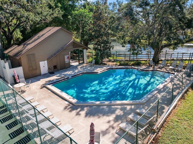 community pool featuring an outbuilding, a patio, and fence