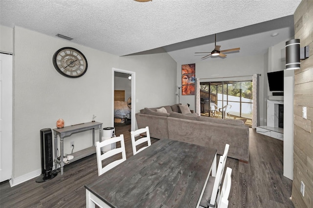 dining room with dark wood-style floors, a fireplace with raised hearth, visible vents, and ceiling fan