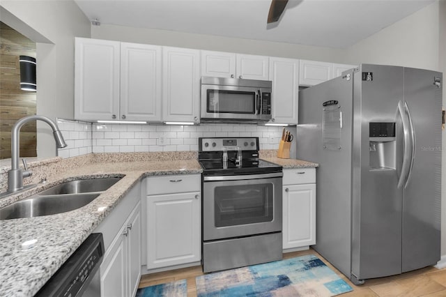 kitchen with a sink, white cabinets, tasteful backsplash, and stainless steel appliances