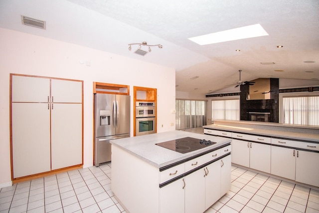 kitchen with vaulted ceiling with skylight, light tile patterned floors, stainless steel appliances, and light countertops