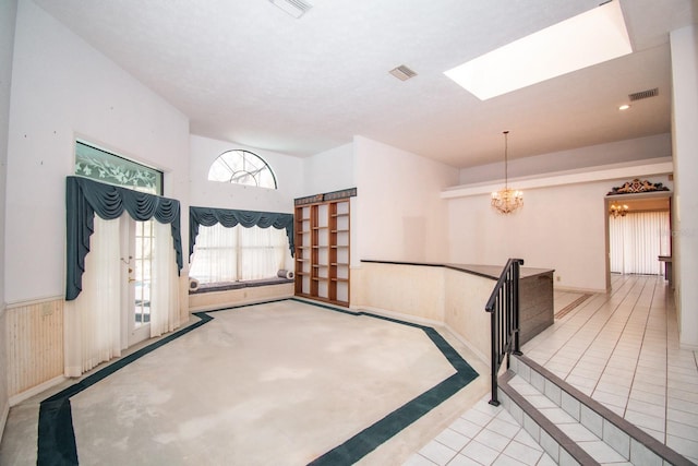 entryway with an inviting chandelier, tile patterned floors, a skylight, and visible vents
