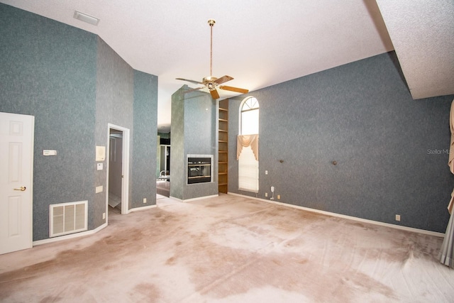 unfurnished living room featuring a multi sided fireplace, carpet, a ceiling fan, and visible vents