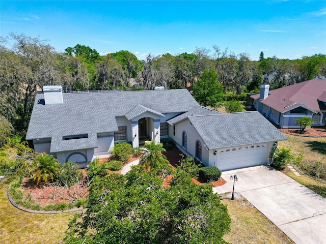 ranch-style house with stucco siding, driveway, a chimney, and a garage