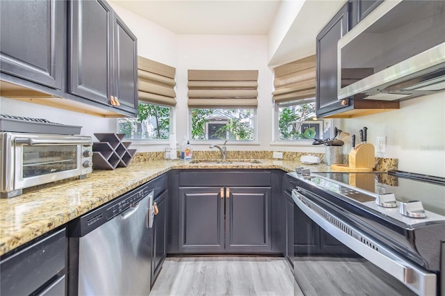506 S Willow Ave Unit 7, Tampa, FL 33606 - kitchen featuring a sink, light wood-style floors, appliances with stainless steel finishes, a toaster, and light stone countertops