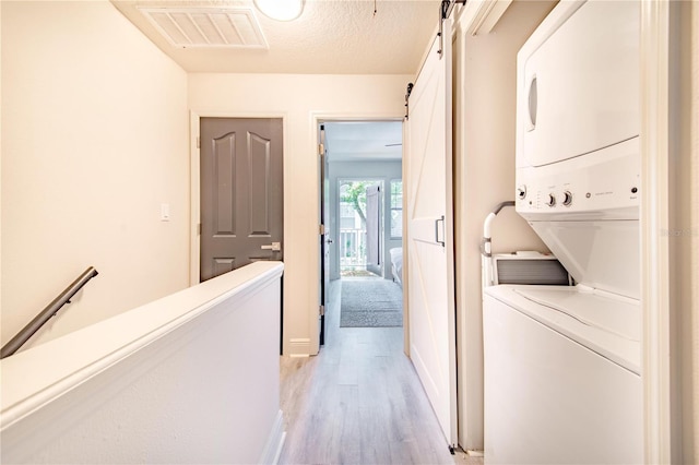 506 S Willow Ave Unit 7, Tampa, FL 33606 - washroom featuring visible vents, stacked washer and dryer, light wood-style flooring, a barn door, and laundry area