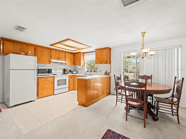 kitchen with light countertops, visible vents, white appliances, a peninsula, and brown cabinetry