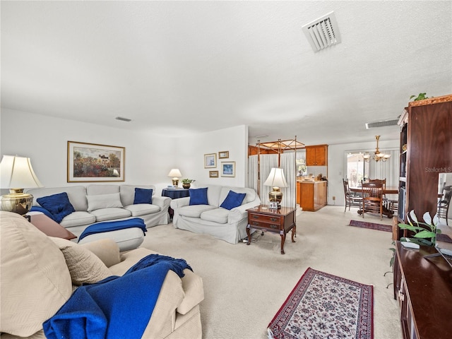 living area featuring visible vents, light colored carpet, and an inviting chandelier
