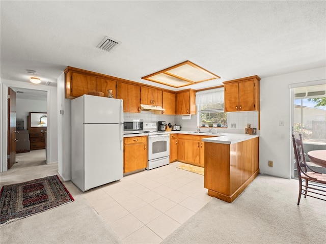 kitchen with decorative backsplash, white appliances, light countertops, under cabinet range hood, and visible vents