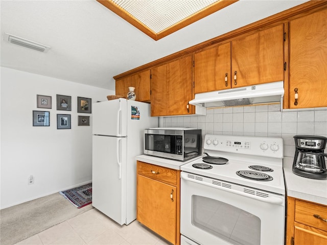 kitchen with brown cabinetry, under cabinet range hood, visible vents, and white appliances