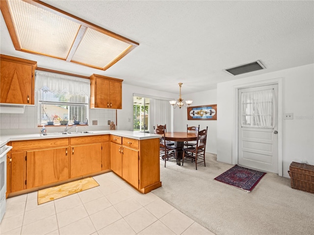 kitchen featuring a chandelier, light countertops, backsplash, a peninsula, and visible vents