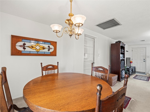 dining area featuring visible vents, carpet flooring, and an inviting chandelier