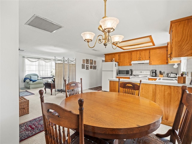 dining room featuring a notable chandelier, visible vents, and light carpet
