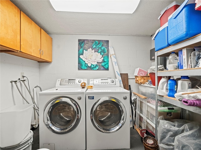 washroom with cabinet space, concrete block wall, and washing machine and clothes dryer