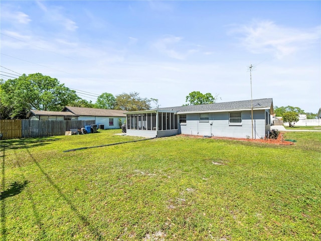 rear view of property featuring fence, a lawn, a sunroom, and concrete block siding