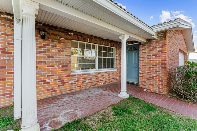entrance to property featuring brick siding and a porch