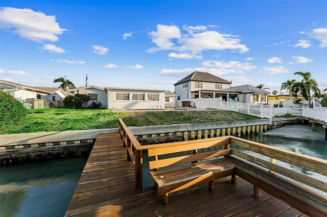 view of dock featuring a residential view, fence, a yard, and a water view