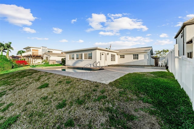 rear view of house featuring stucco siding, a lawn, a fenced backyard, and a patio area
