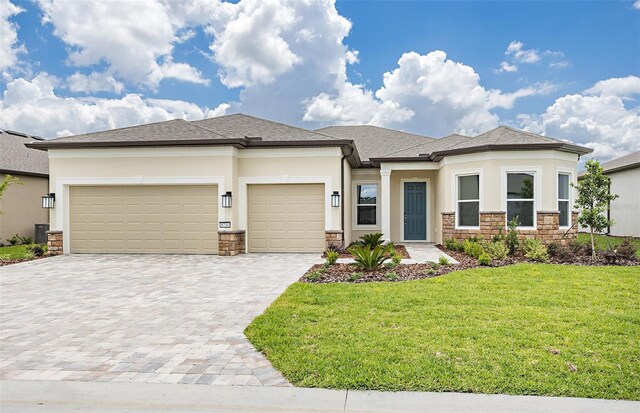 prairie-style house featuring stucco siding, decorative driveway, and stone siding