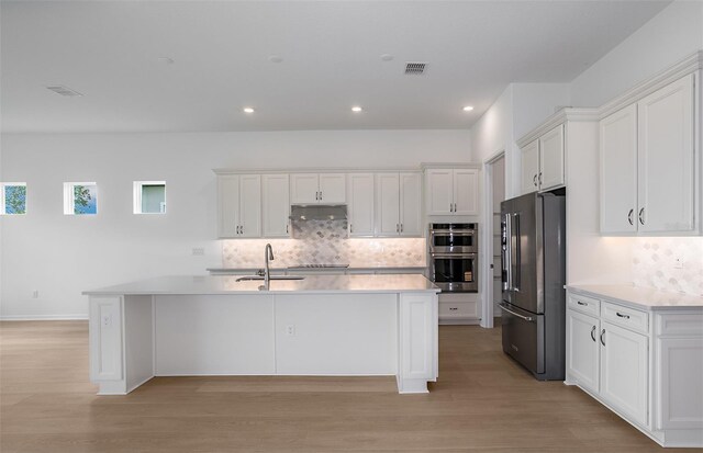 kitchen featuring under cabinet range hood, stainless steel appliances, white cabinets, and visible vents