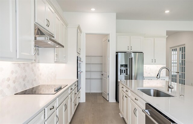 kitchen featuring a sink, appliances with stainless steel finishes, white cabinets, and light countertops