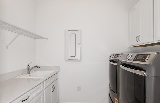 laundry area featuring a sink, cabinet space, electric panel, and washer and dryer