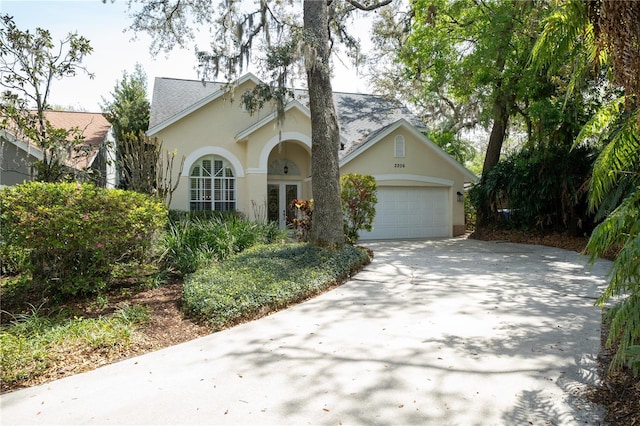 2206 Green Oaks Ln, Tampa, FL 33612 - view of front of house featuring stucco siding, an attached garage, french doors, driveway, and a shingled roof