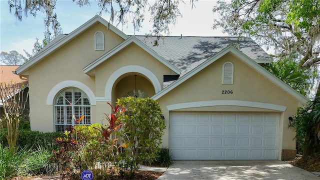 2206 Green Oaks Ln, Tampa, FL 33612 - view of front of property with stucco siding, a shingled roof, an attached garage, and driveway