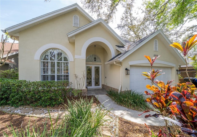 2206 Green Oaks Ln, Tampa, FL 33612 - view of front of house featuring stucco siding, an attached garage, and french doors