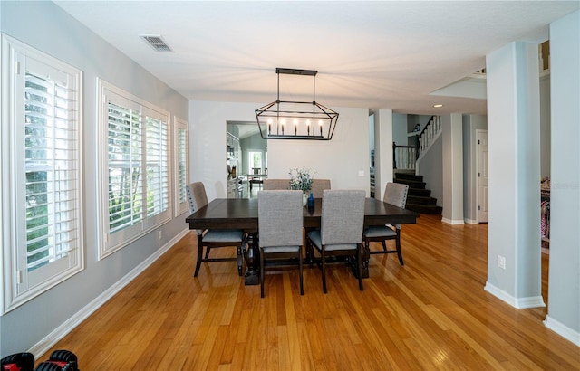 2206 Green Oaks Ln, Tampa, FL 33612 - dining area with stairway, light wood-type flooring, baseboards, visible vents, and an inviting chandelier