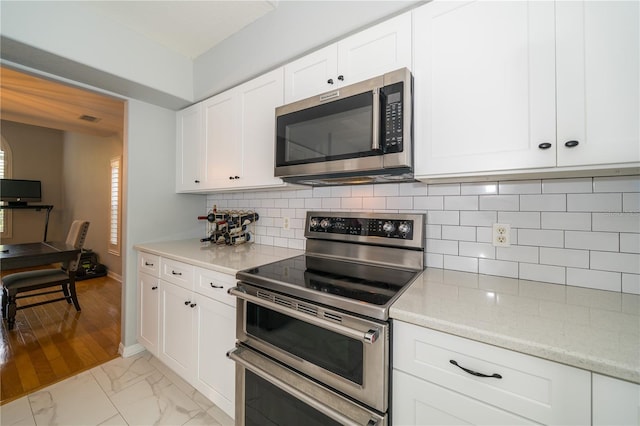 2206 Green Oaks Ln, Tampa, FL 33612 - kitchen featuring tasteful backsplash, stainless steel appliances, marble finish floor, visible vents, and white cabinets