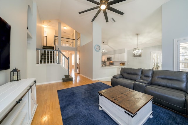 2206 Green Oaks Ln, Tampa, FL 33612 - living room with stairway, baseboards, ceiling fan with notable chandelier, visible vents, and light wood-style floors