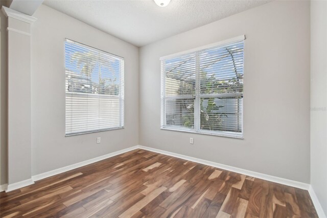 12304 Silton Peace Dr, Riverview, FL 33579 - empty room featuring dark wood finished floors, baseboards, ornate columns, and a textured ceiling