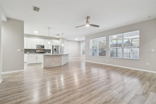 12304 Silton Peace Dr, Riverview, FL 33579 - unfurnished living room featuring light wood-type flooring, visible vents, baseboards, and ceiling fan