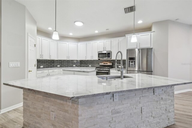 12304 Silton Peace Dr, Riverview, FL 33579 - kitchen featuring light wood-type flooring, visible vents, tasteful backsplash, a spacious island, and appliances with stainless steel finishes
