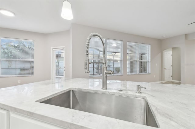 12304 Silton Peace Dr, Riverview, FL 33579 - kitchen with a sink, light stone counters, and arched walkways