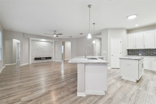 12304 Silton Peace Dr, Riverview, FL 33579 - kitchen featuring decorative backsplash, arched walkways, a kitchen island with sink, and a sink