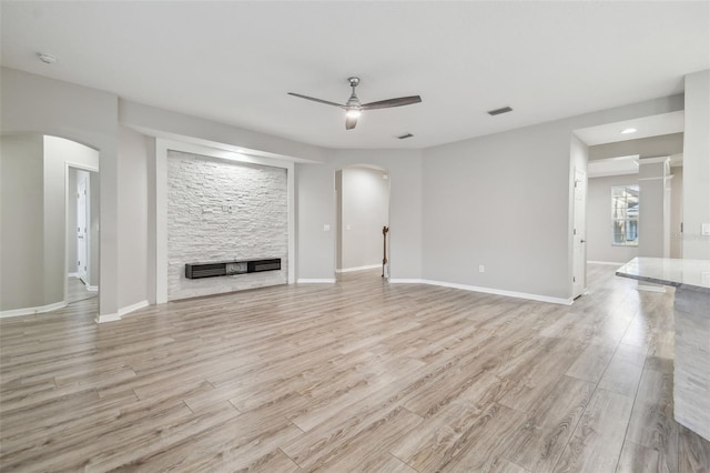 12304 Silton Peace Dr, Riverview, FL 33579 - unfurnished living room featuring arched walkways, ceiling fan, a fireplace, and light wood finished floors