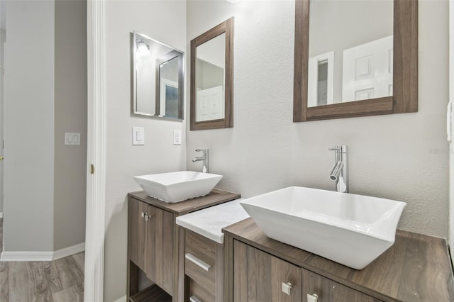 12304 Silton Peace Dr, Riverview, FL 33579 - bathroom featuring two vanities, wood finished floors, baseboards, and a sink