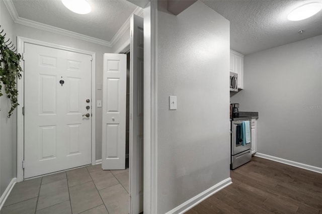 kitchen featuring crown molding, appliances with stainless steel finishes, wood finished floors, a textured ceiling, and white cabinetry