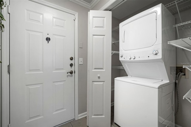 washroom featuring stacked washer / drying machine, laundry area, and tile patterned flooring