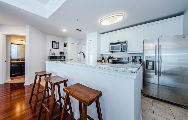 700 S Harbour Island Blvd Unit 404, Tampa, FL 33602 - kitchen with visible vents, light stone countertops, a kitchen bar, appliances with stainless steel finishes, and white cabinetry
