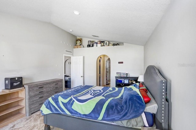bedroom with visible vents, arched walkways, vaulted ceiling, and a textured ceiling