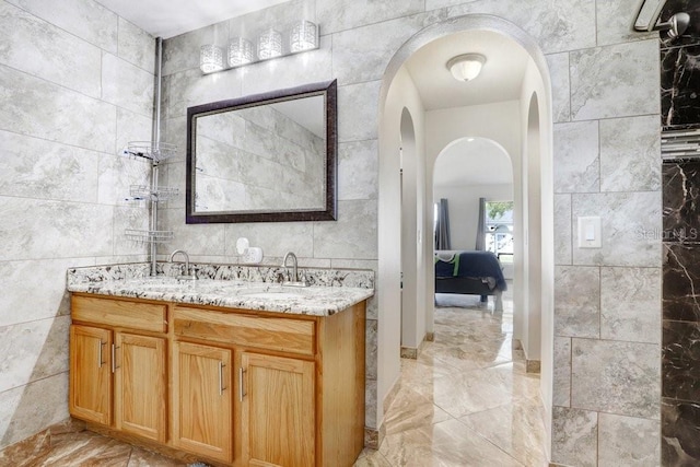 full bathroom featuring tile walls, double vanity, and a sink